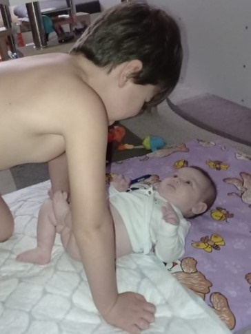 dítě srovnané kouká přímo nahoru na staršího bratra