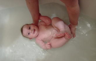 matka drží dítě ve vaně